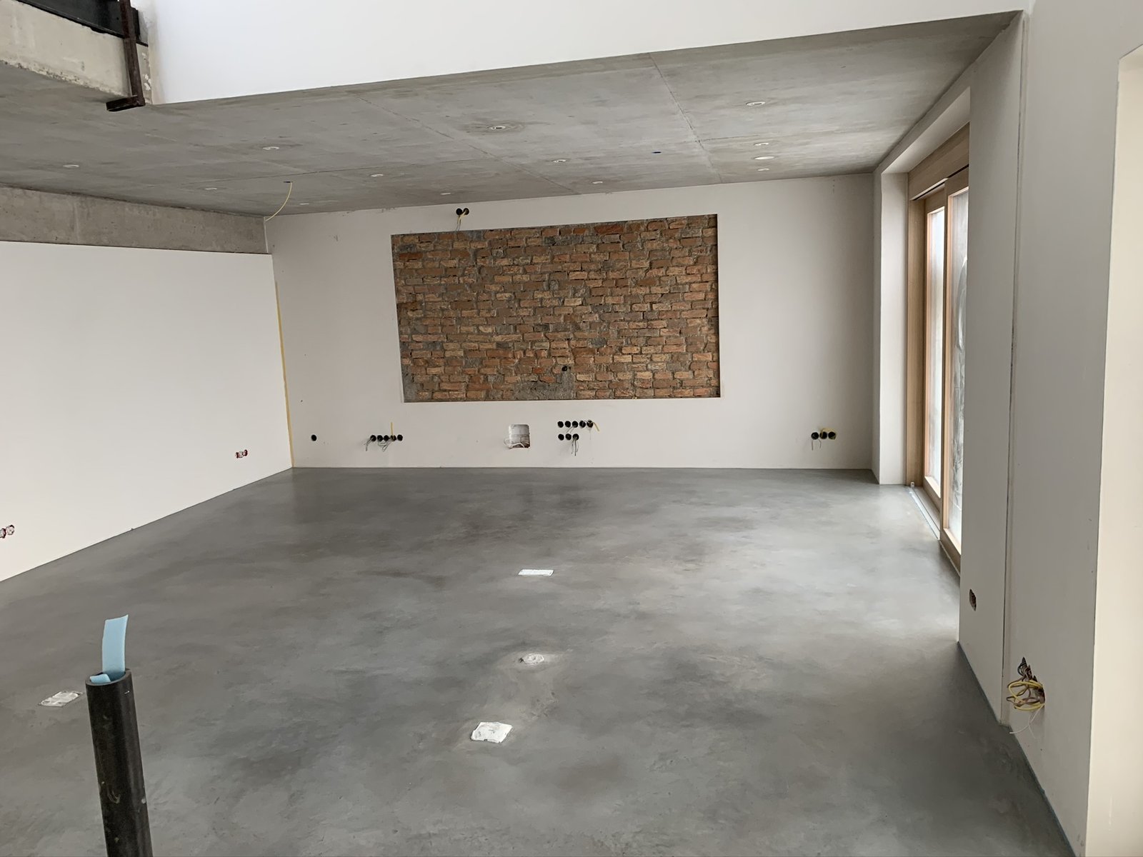 Sichtestrich in Hellgrau in einem minimalistischen Raum mit Sichtmauerwerk